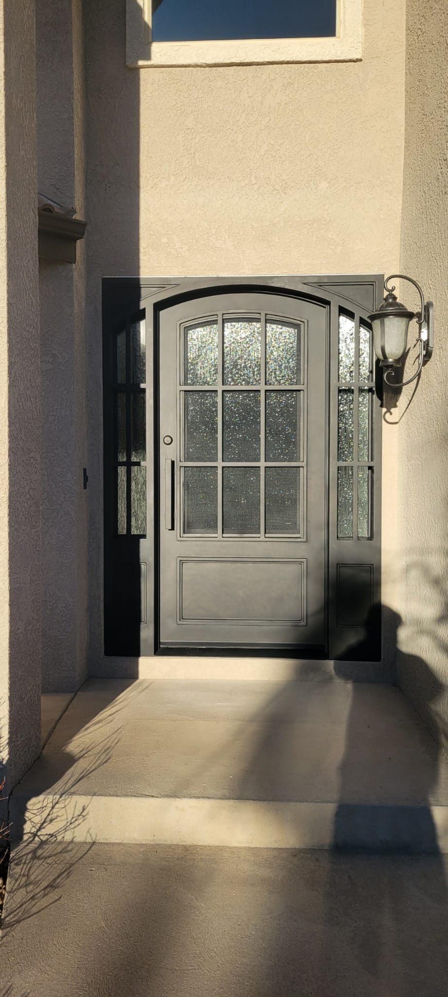 Arched iron door with textured glass sidelights