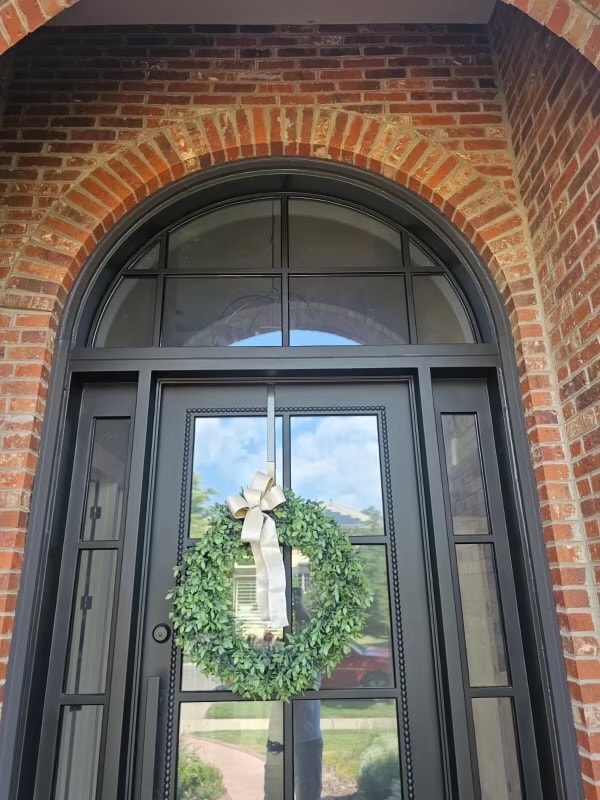 Arched iron door brick home with wreath