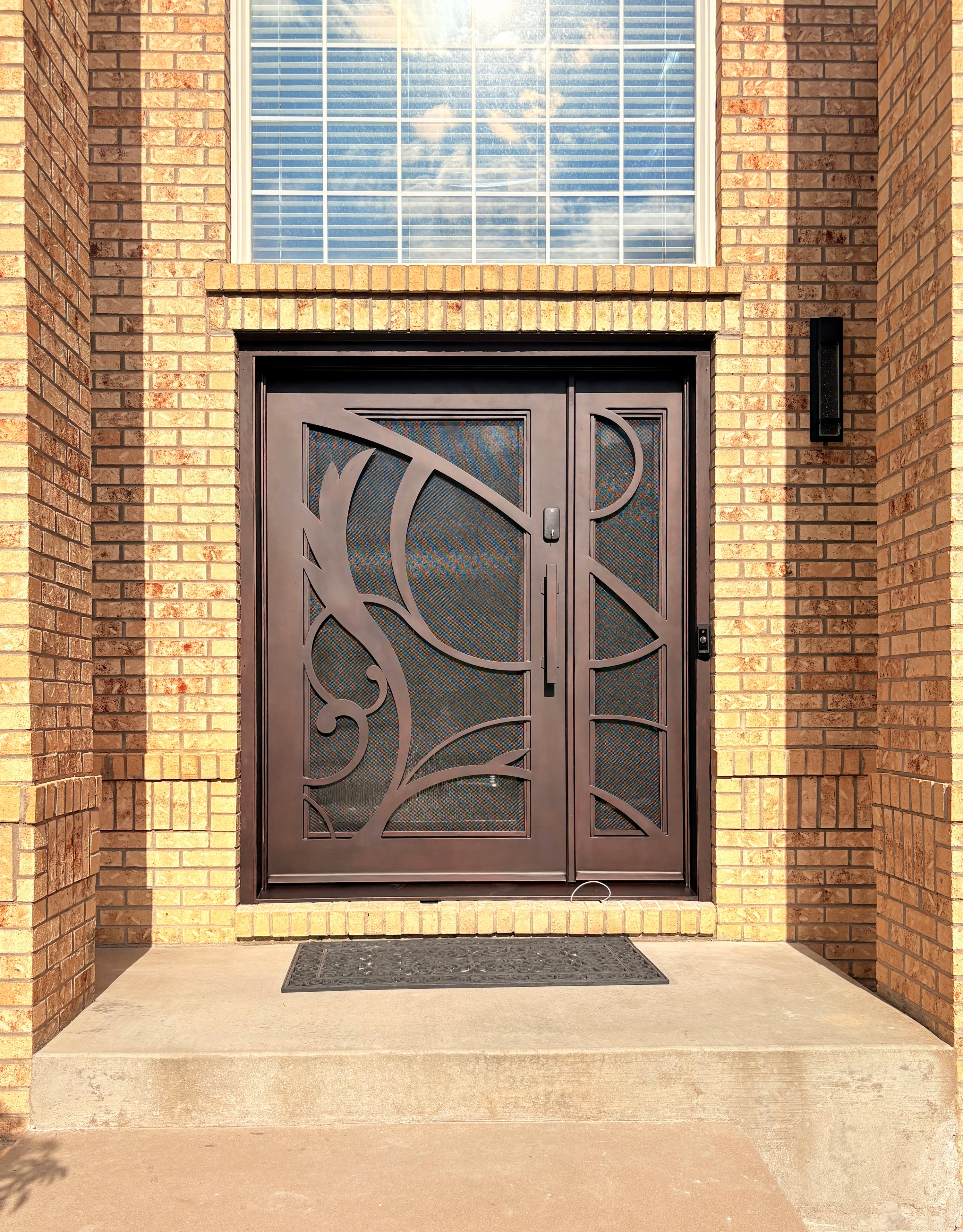 After — custom iron door with flowing scrollwork design, exterior view