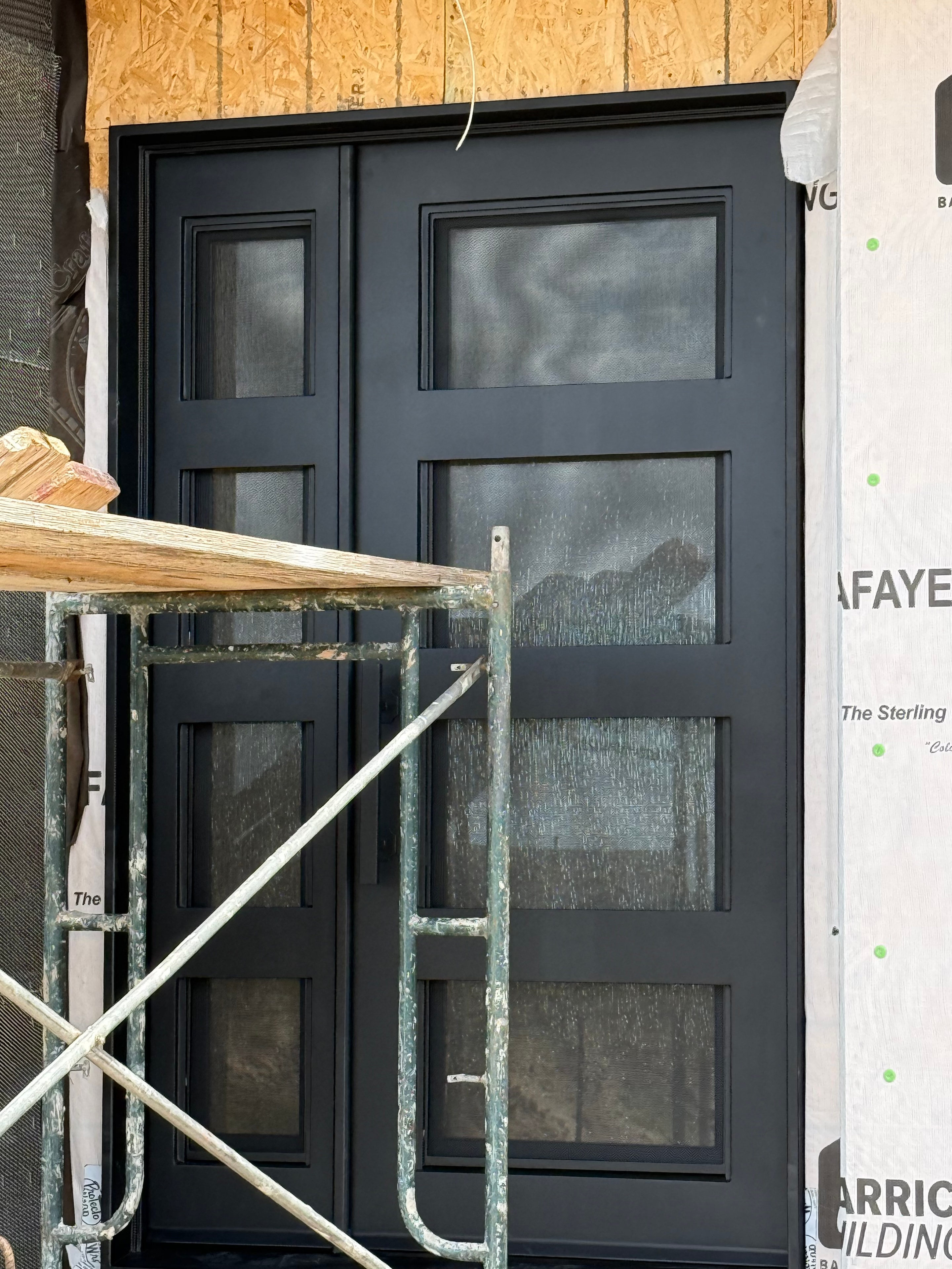 Black iron garage door with glass panels under construction